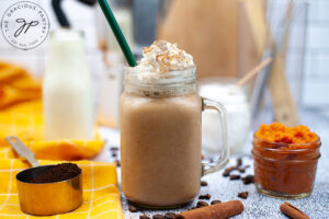 The finished Sugar Free Pumpkin Spice Coffee Creamer mixed into a latte, topped with whipped cream and cinnamon in a glass mug.