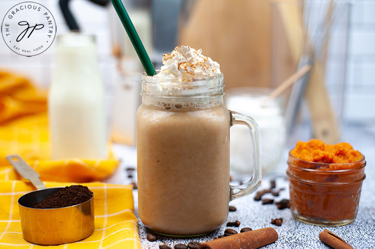 The finished latte, topped with whipped cream and cinnamon in a glass mug.