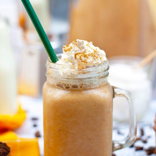 A latte mixed with this Sugar Free Pumpkin Spice Coffee Creamer, in a glass mug topped with whipped cream and cinnamon.