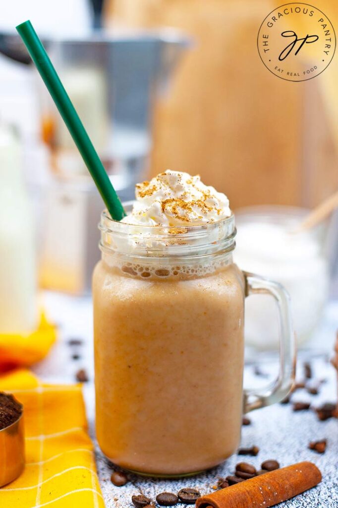 A latte mixed with this Sugar Free Pumpkin Spice Coffee Creamer, in a glass mug topped with whipped cream and cinnamon.