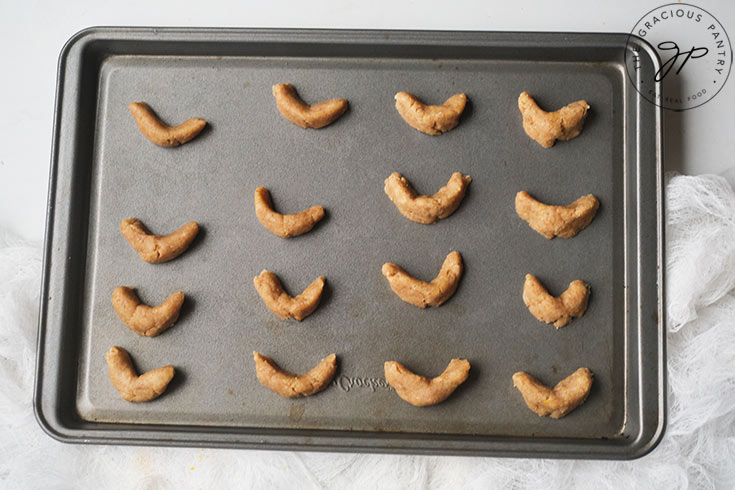Unbaked horn cookies sitting on a cookie sheet.