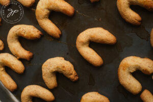 Just-baked Almond Horns on a cookie sheet.