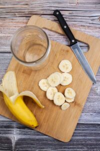 A half-sliced banana on a cutting board.