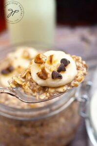 A spoon lifts some of this Banana Bread Oatmeal Recipe out of a canning jar, towards the camera.