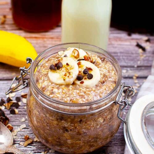 A full canning jar filled with this Banana Bread Oatmeal Recipe and topped with banana slices, chocolate chips and chopped pecans.