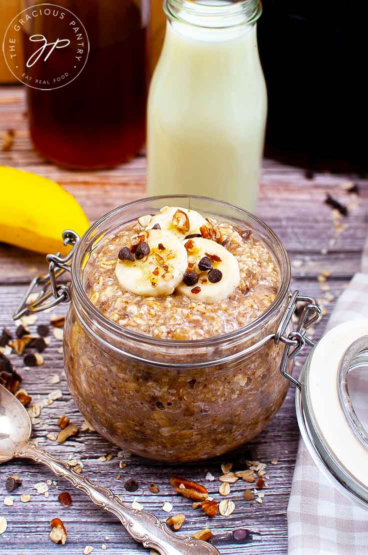A full canning jar filled with this Banana Bread Oatmeal Recipe and topped with banana slices, chocolate chips and chopped pecans.