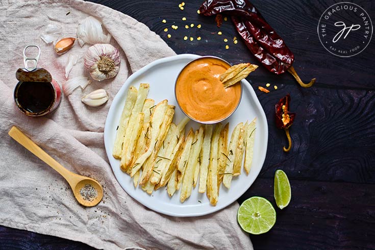 The finished Chipotle Aioli served in a small bowl on a white plate of fries.