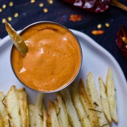 An overhead shot looking down on a white plate that holds french fries and a small bowl of Chipotle Aioli.