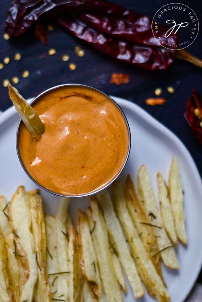 An overhead shot looking down on a white plate that holds french fries and a small bowl of Chipotle Aioli.