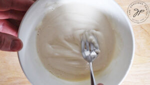 Mixing the icing in a small, white bowl.