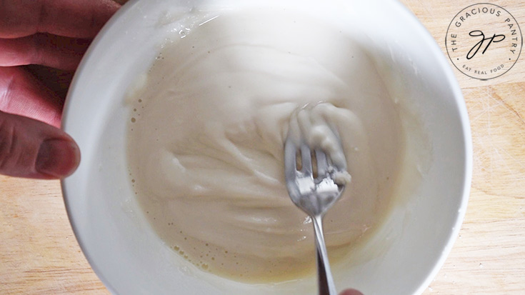 Mixing the icing in a small, white bowl.