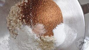 Flour and other dry ingredients sitting in a metal mixing bowl.