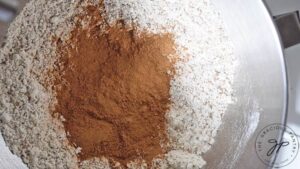 Gingerbread spices added to dry ingredients in a mixing bowl.