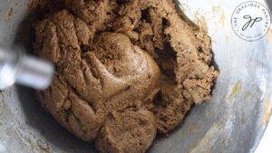 Fully mixed gingerbread dough in a metal mixing bowl.