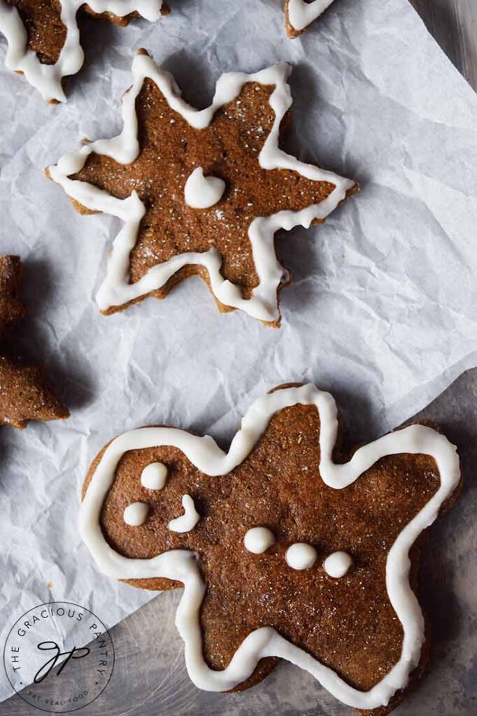 An overhead shot looking down on decorated healthy gingerbread cookies sitting on white parchment paper.