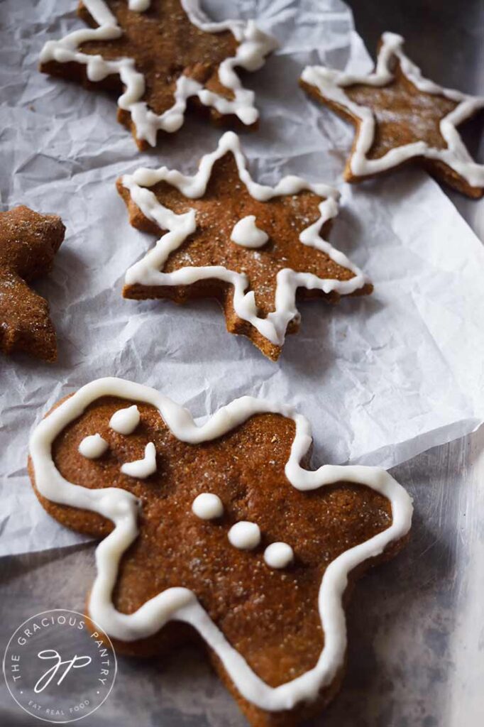 A collection of iced gingerbread cookies laying on parchment paper.