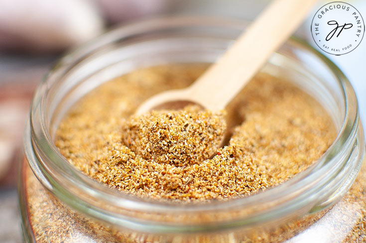 The finished Homemade Fajita Seasoning in an open jar with a small scoop sitting inside.