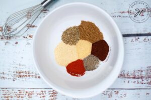 All the Homemade Fajita Seasoning spices sitting in small piles inside a white bowl.