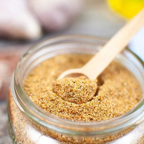 Homemade Fajita Seasoning in an open jar with a small scoop resting inside.