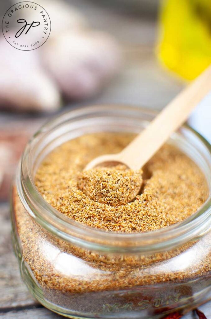 Homemade Fajita Seasoning in an open jar with a small scoop resting inside.