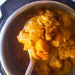 A close up of a ladle filled with Jamaican Curry Chicken.