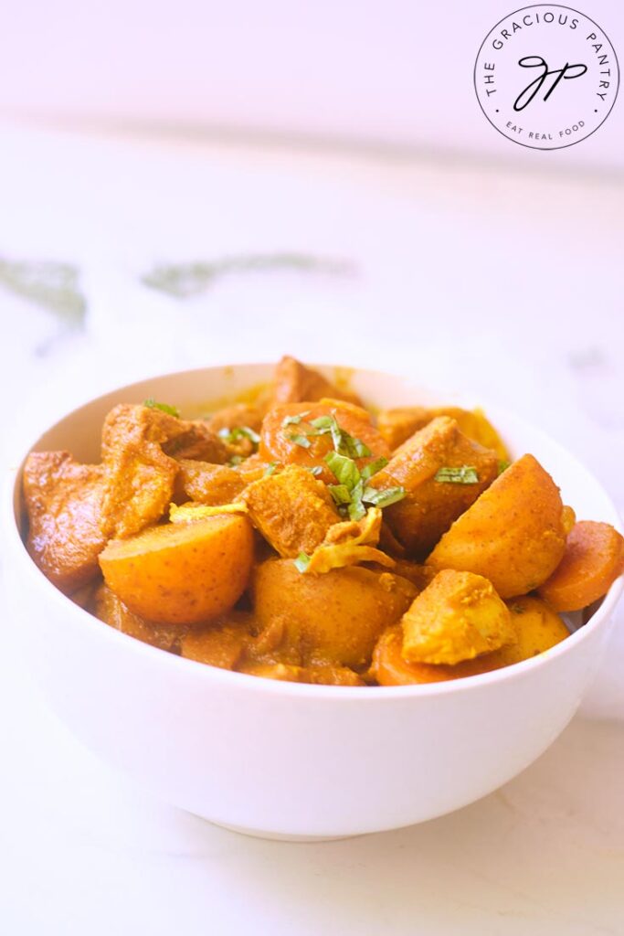 A white bowl filled with Jamaican Curry Chicken, sitting on a white background.