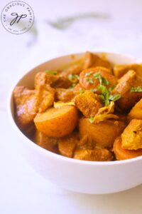 A side view of a white bowl filled with this Jamaican Curry Chicken Recipe.
