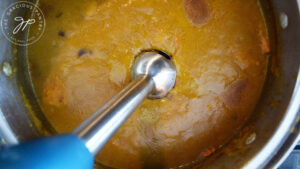 Blending the just cooked Kabocha Squash Soup with a stick blender.