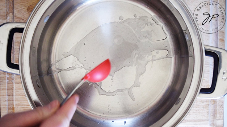 Adding oil to a stainless steel soup pot.