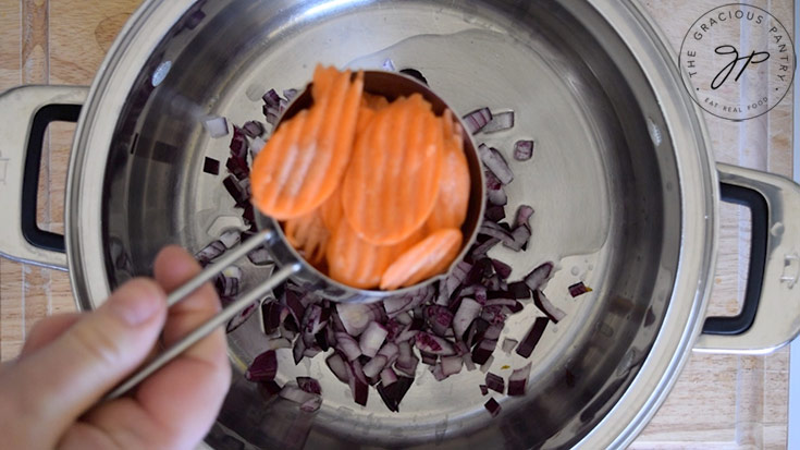 Adding sliced carrots to a soup pot.