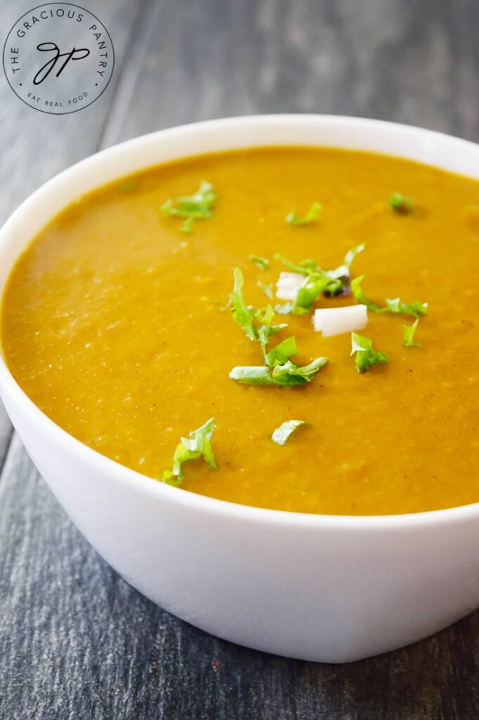 A white bowl filled with Kabocha Squash Soup, sits on a gray background.