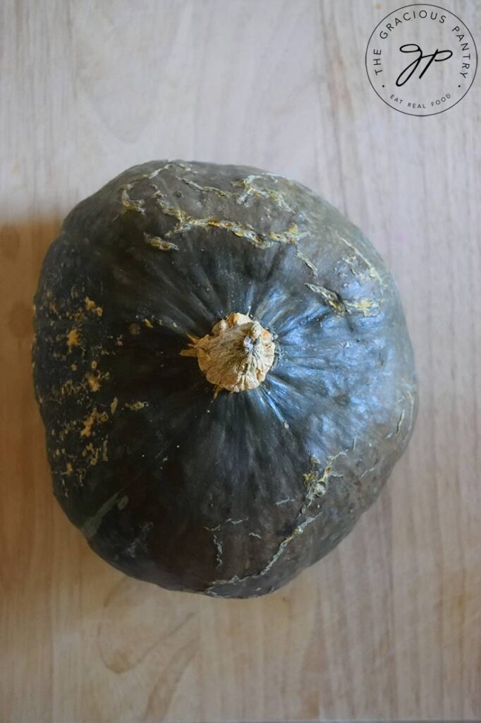 And overhead view looking down on a whole Kabocha squash, which sits on a wooden surface.