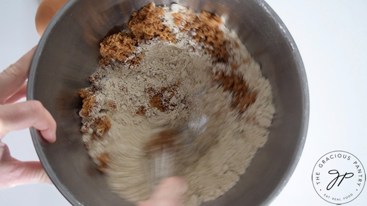 Dry ingredients being whisked together in a stainless steel mixing bowl.