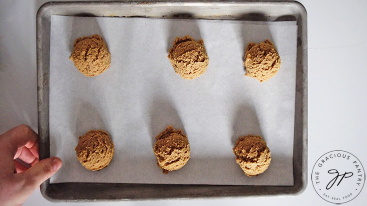 Pfeffernusse Cookies lined up on a parchment-lined cookie sheet.