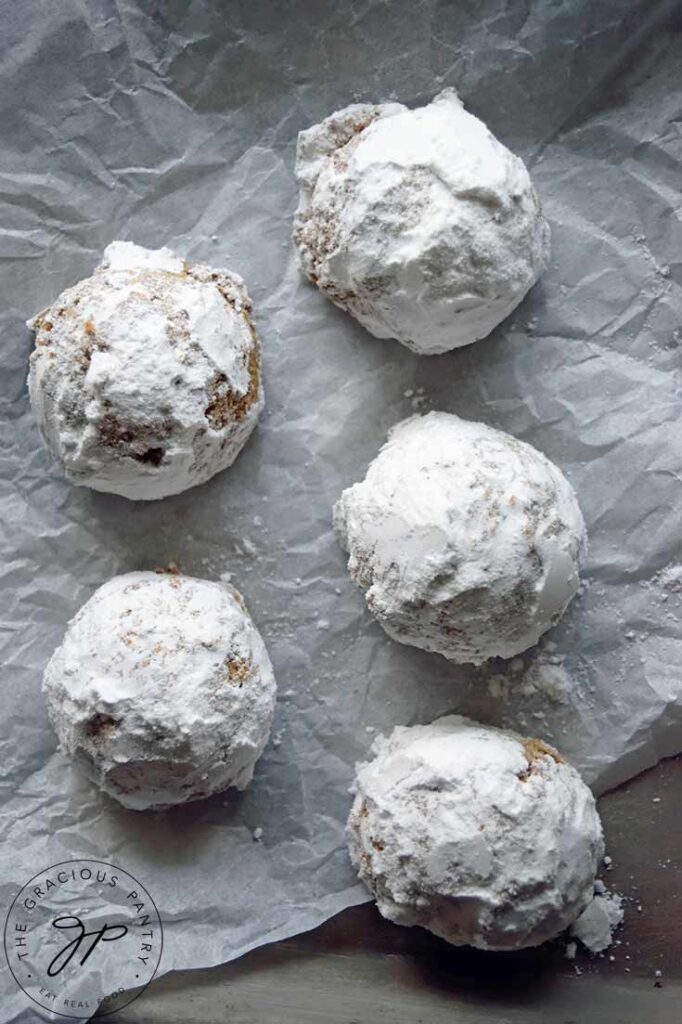 Pfeffernusse Cookies lined up on a piece of parchment.