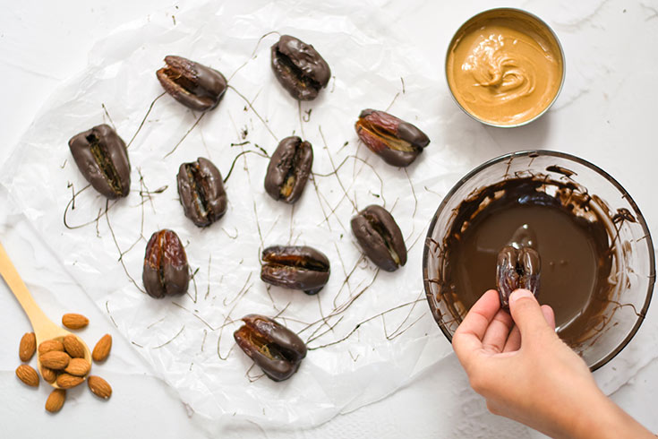 Dipping a pitted date into melted chocolate.