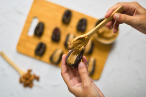 Filling a date with peanut butter using a small wooden spoon.