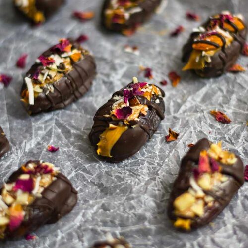 Stuffed Dates sitting on a piece of wrinkled parchment paper and topped with dried rose petals.