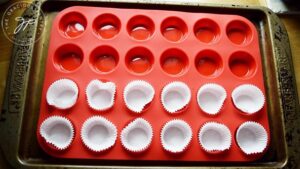 Paper liners sitting in a red, mini muffin pan.
