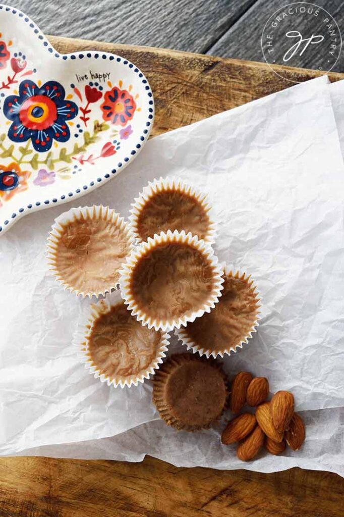 An overhead view looking down onto a pile of Almond Butter Fat Bombs and a few whole almonds resting on a piece of parchment paper.