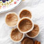 A stack of Almond Butter Fat Bombs sits on a piece of parchment paper which sits on a wooden cutting board.