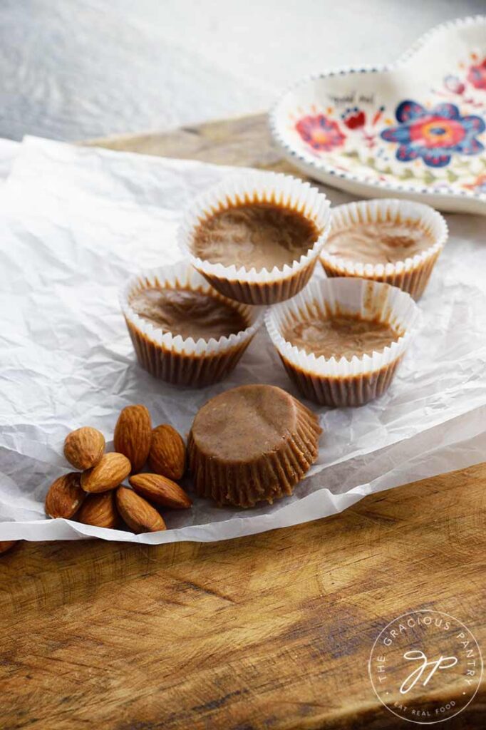 Several Almond Butter Fat Bombs rest on piece of parchment paper, on top of a wooden surface.