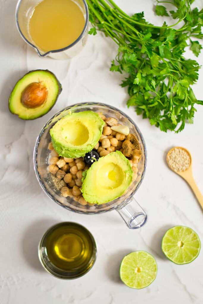 Chickpeas and an avocado in a food processor bowl.