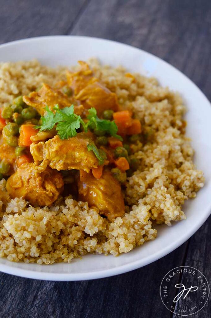 Coconut Curry Chicken served over cooked quinoa, served in a white bowl.