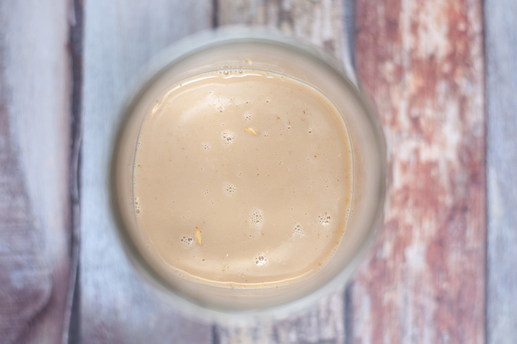 Milk and coffee added to oats in a canning jar.