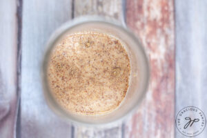 Vanilla extract and maple syrup added to oats and milk in a canning jar.