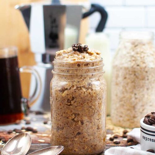 A canning jar sits on a table, stuffed with this Coffee Overnight Oats Recipe.