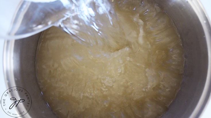 Water being poured into a stock pot with chicken broth for making this German Cabbage Soup recipe.