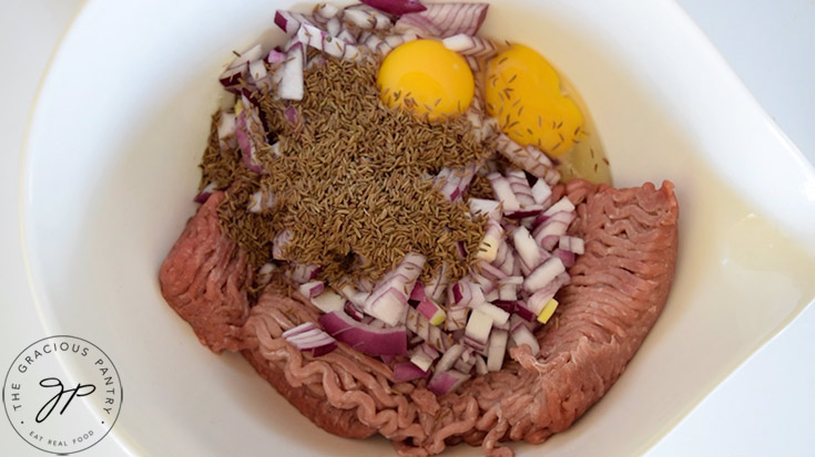 All the meatball ingredients added to a white mixing bowl.