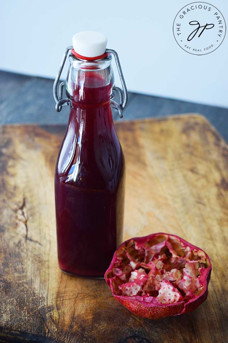 A capped, clear, glass bottle filled with Grenadine Syrup sits on a cutting board.
